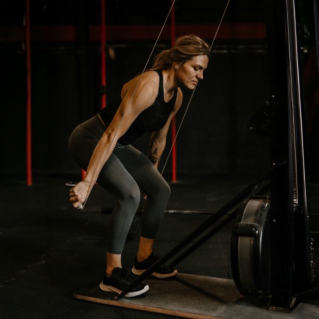 Fit woman lifting barbell in gym using proper deadlift form