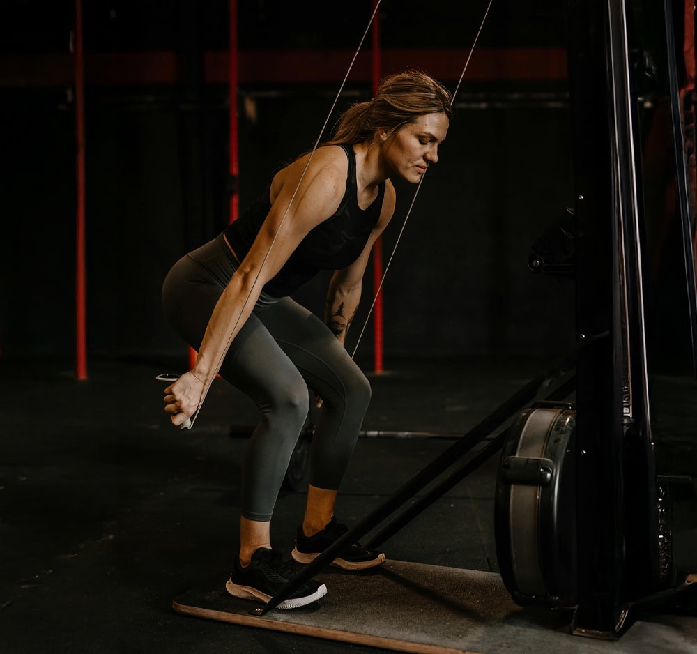 Fit woman lifting barbell in gym using proper deadlift form