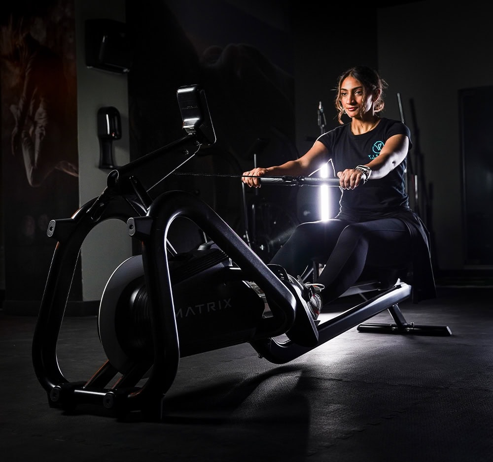 Woman doing indoor cycling in dark gym with neon lights