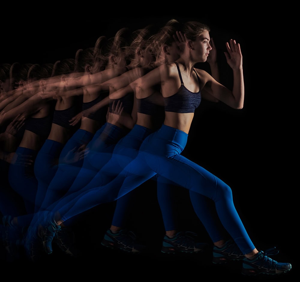 Woman running with blue motion blur in dark fitness studio