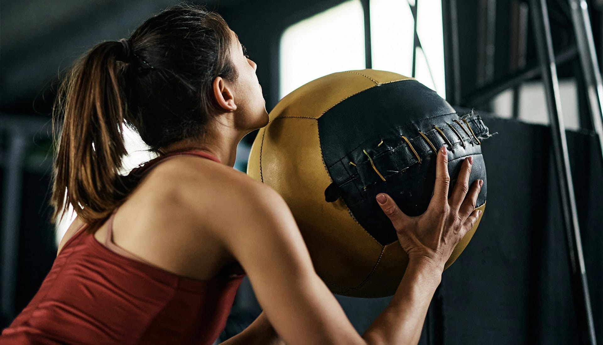 Woman lifting medicine ball in gym during functional training