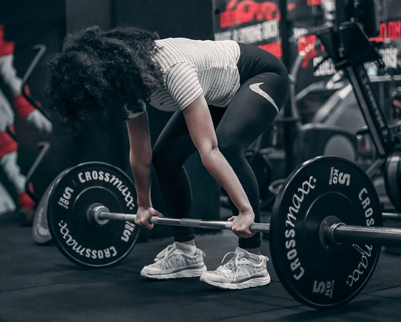 Young woman performing a deadlift with a loaded barbell at the gym