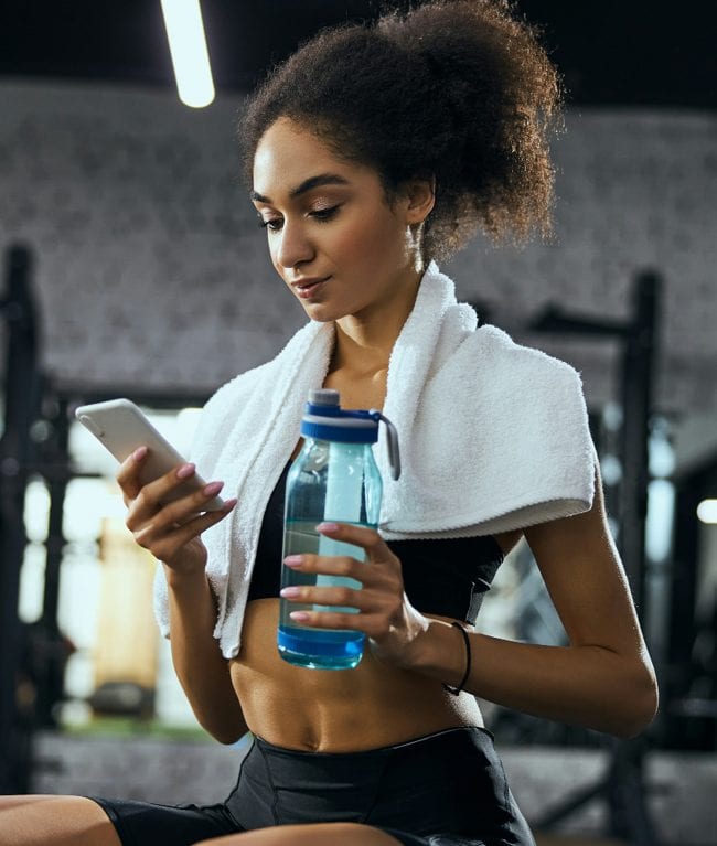 Woman drinking water while resting during gym workout