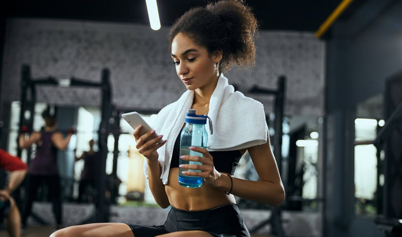 Woman drinking water while resting during gym workout