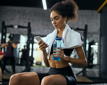 Woman in white towel sipping water after lifting session