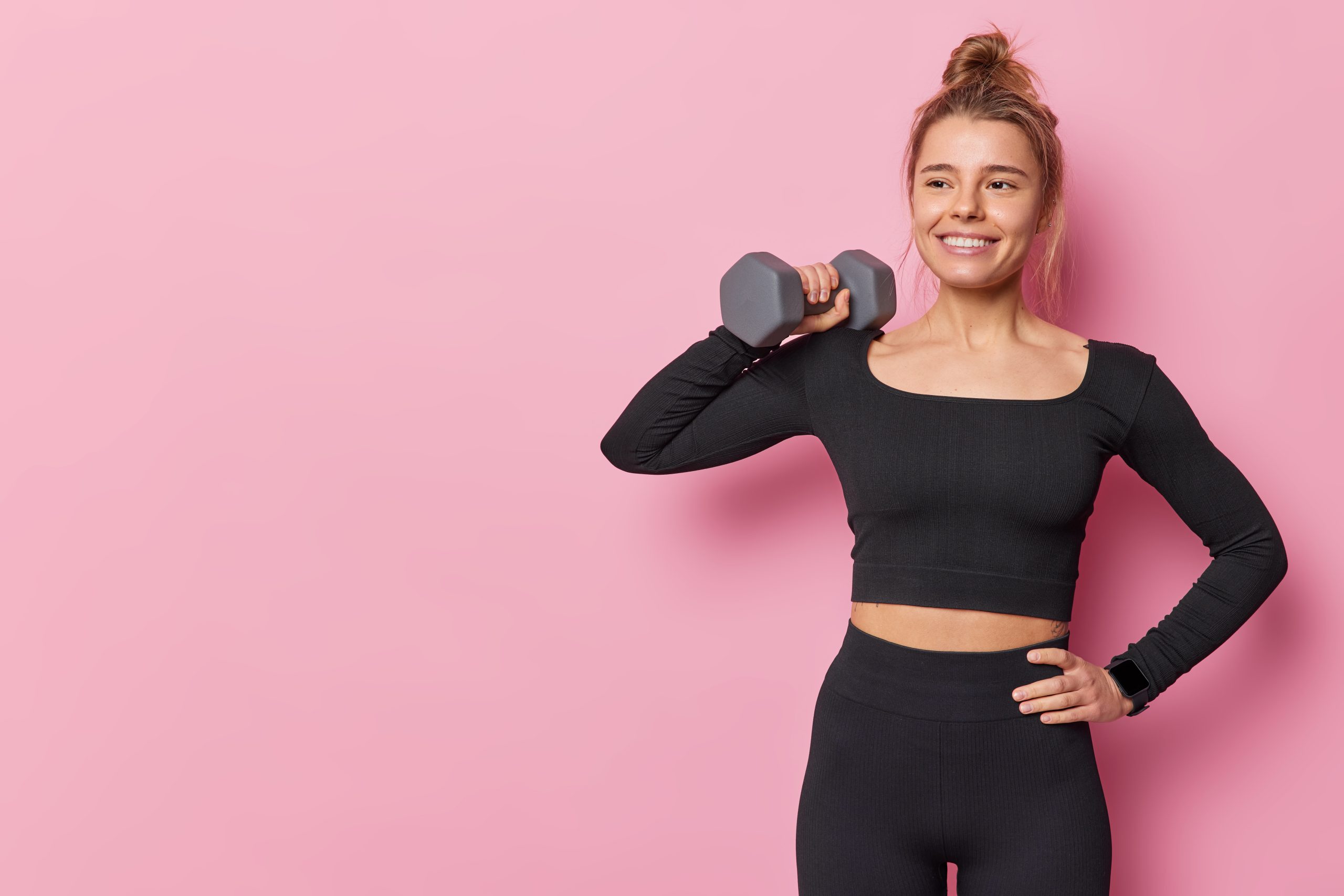 Confident woman in a black fitness outfit holding a dumbbell, representing empowerment at a women-only fitness in Dubai.