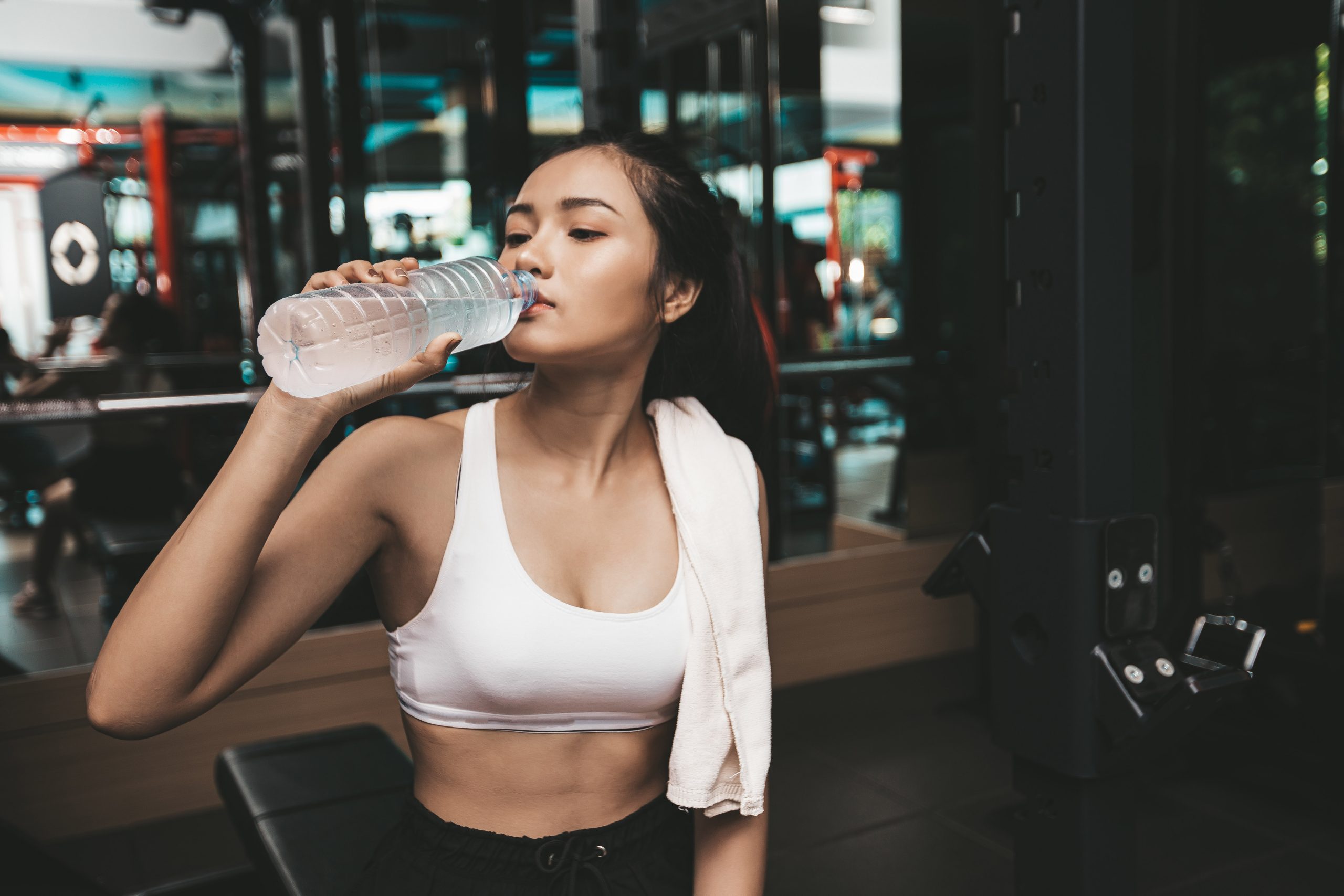 Active woman drinking water after a workout, representing the importance of women’s hydration for energy, recovery, and skin health.