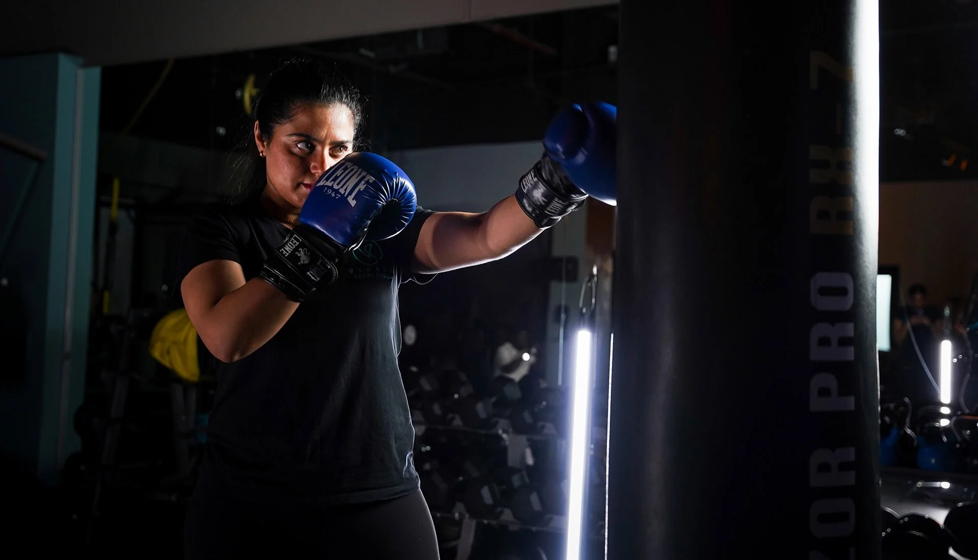 Female boxer training with gloves under neon lights